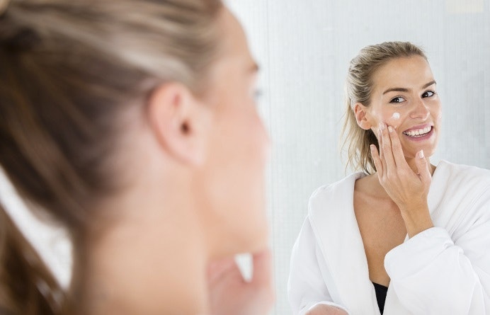 Beautiful woman putting cream